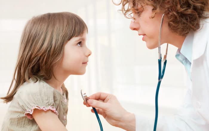 Physician with a stethescope examining a child.