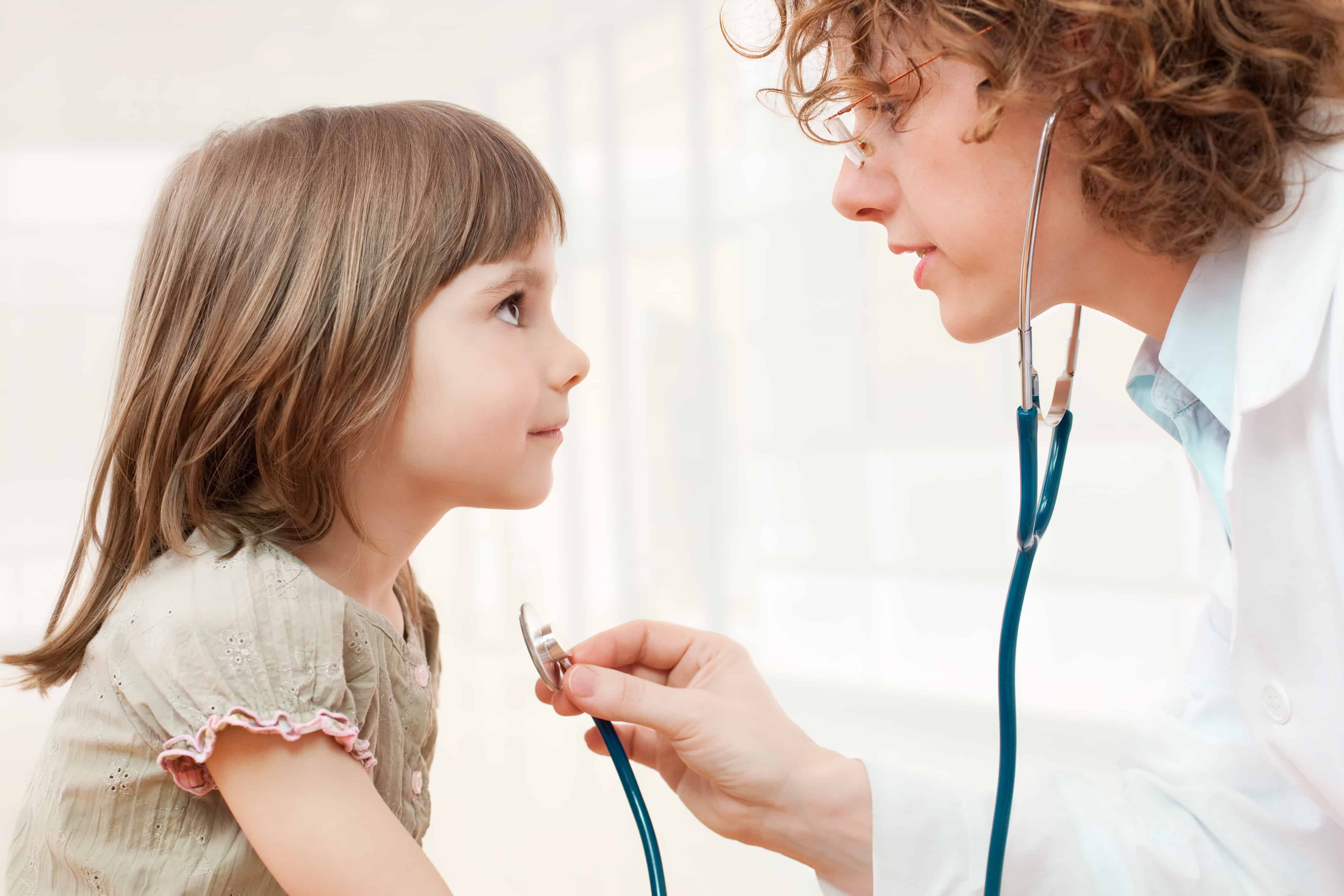 Physician with a stethescope examining a child.