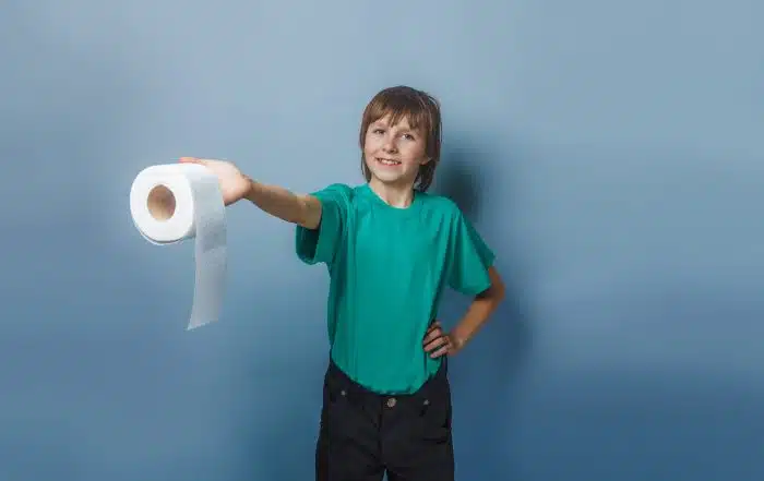 Child holding out a roll of toilet paper